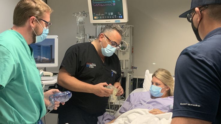 Samer Elbabaa, MD, a pediatric neurosurgeon at Orlando Health, shows expecting parents Jocelyn and Jared Rodriguez a 3D-printed model of their developing baby. Orlando Health surgeons are using the models to prepare for an in-utero procedure to correct spina bifida, a birth defect that occurs when the spinal cord fails to close normally during development.